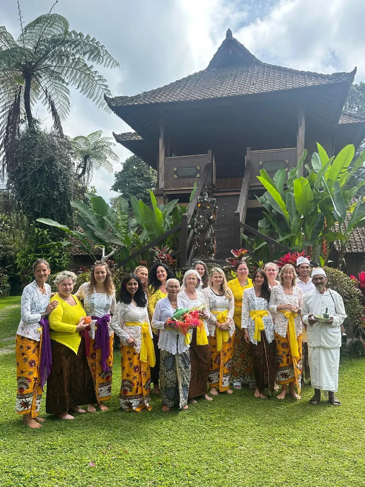 Guests in kebaya with village priests below a tall raised timber house