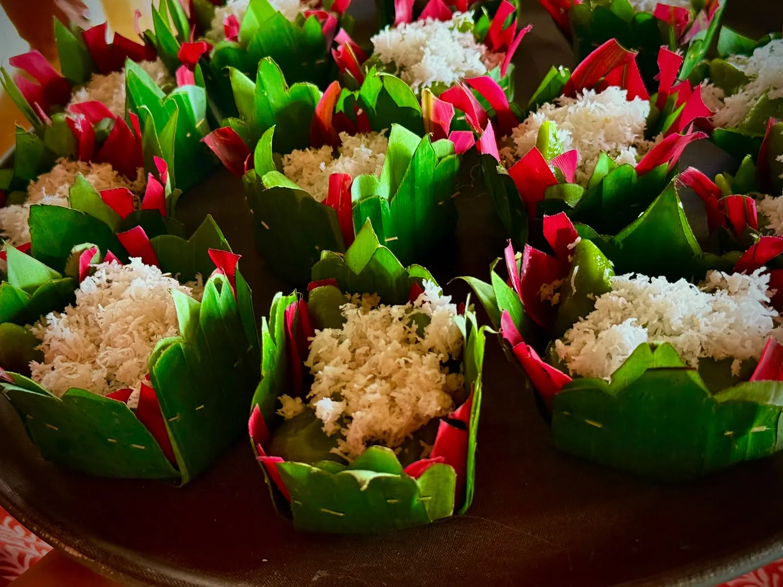 Balinese rice cakes in hand-pinned banana-leaf cups topped with grated coconut