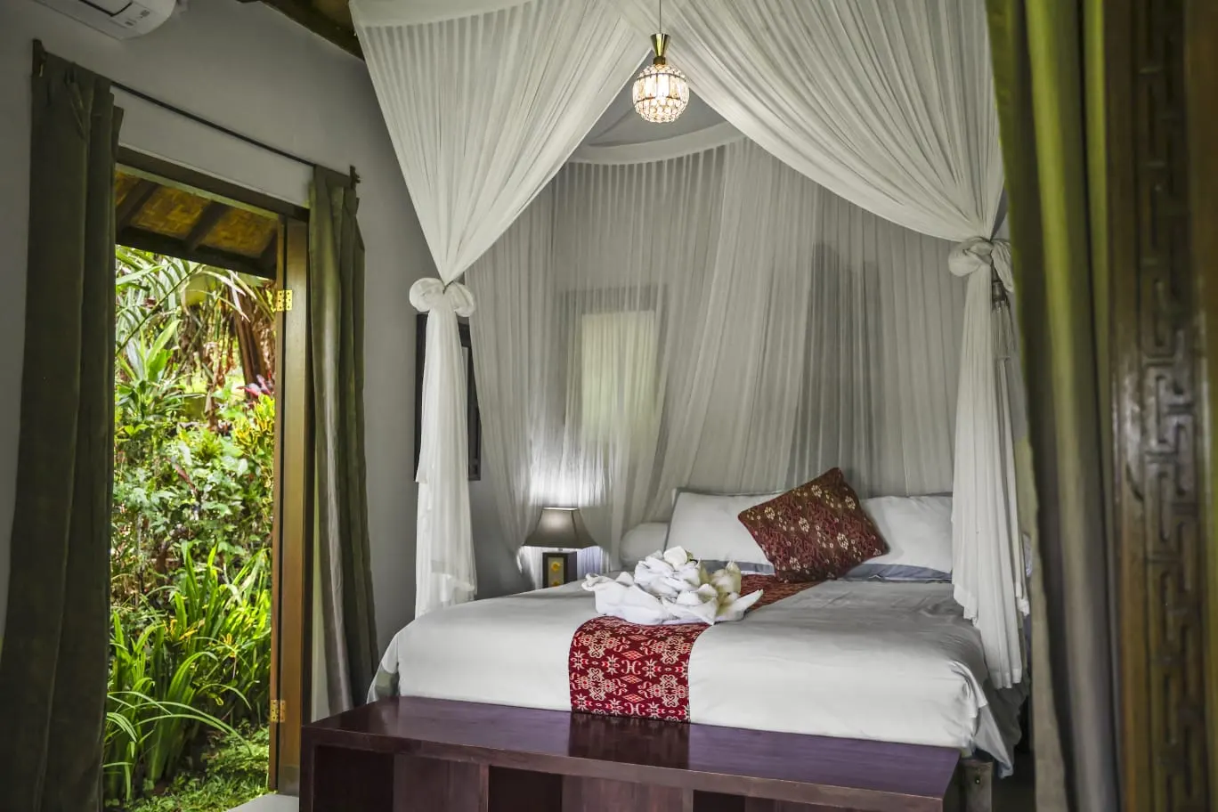 A draped four-poster bed opening to the rainforest