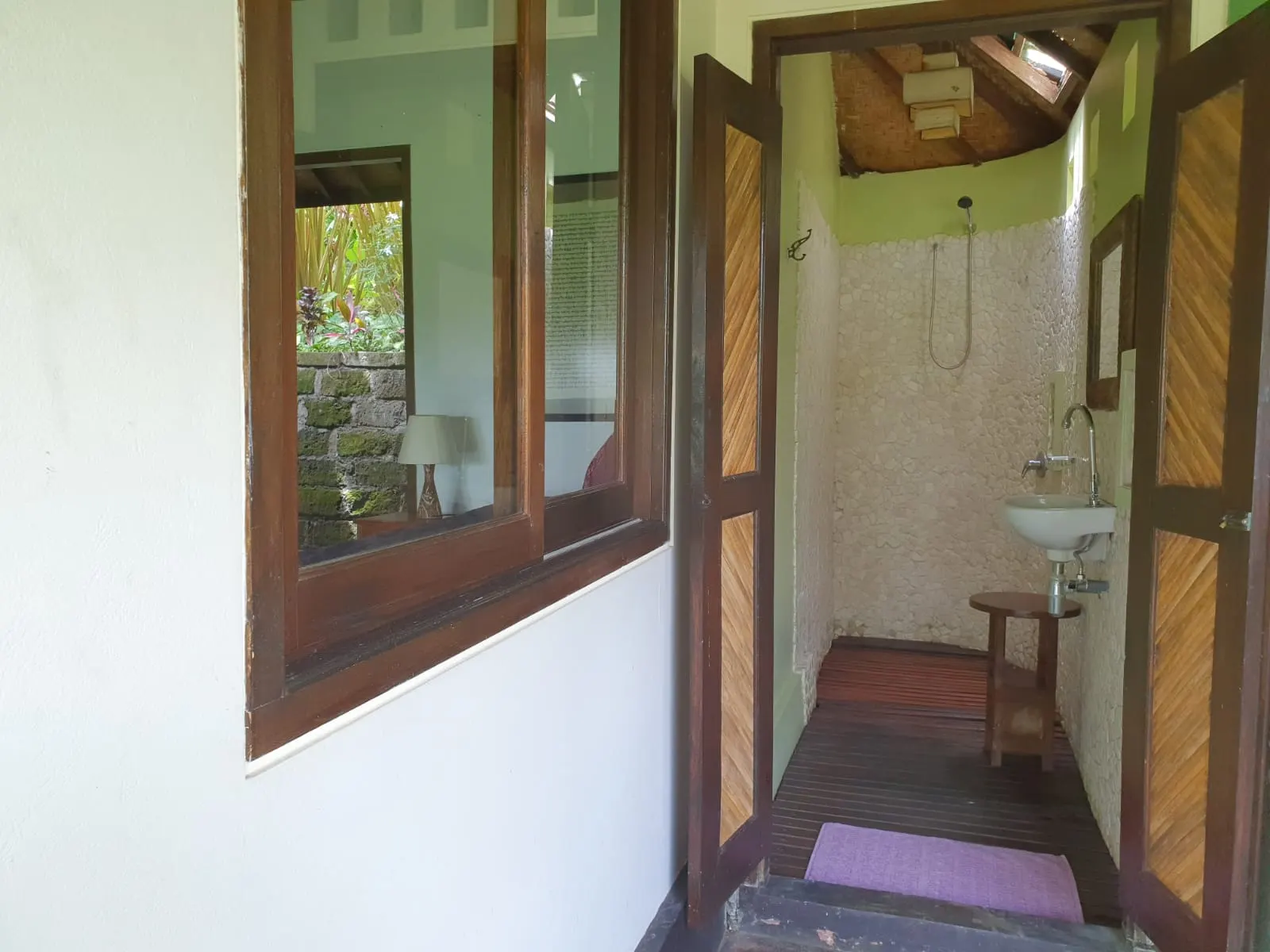 A teak-framed window and the passage to the Lotus House bathroom