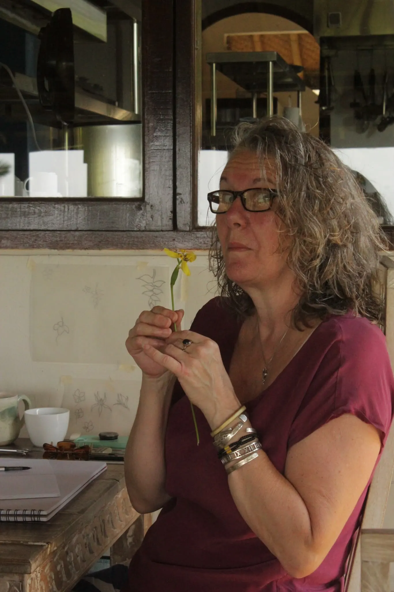 A guest holding a small yellow flower beside her botanical sketches