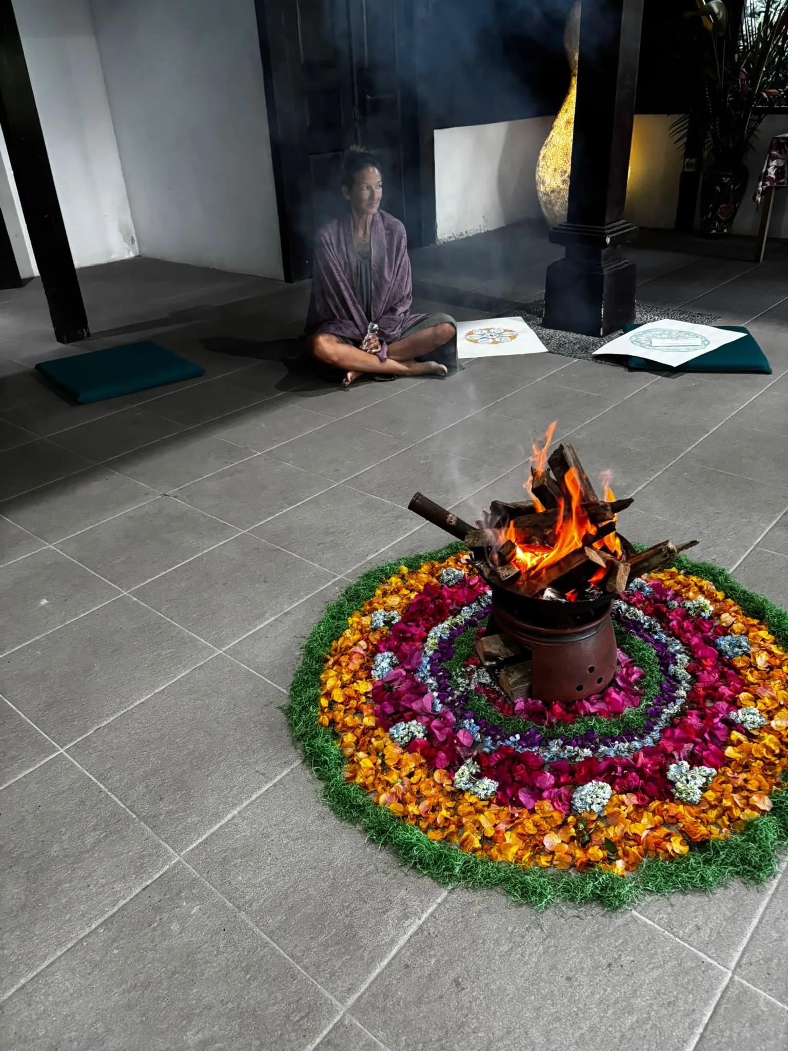 A fire burning on a flower-petal mandala during an evening ceremony