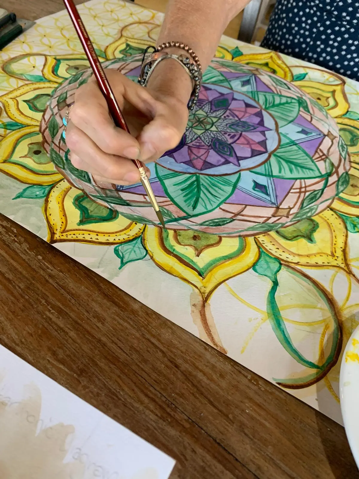 A hand painting fine detail on a watercolour mandala