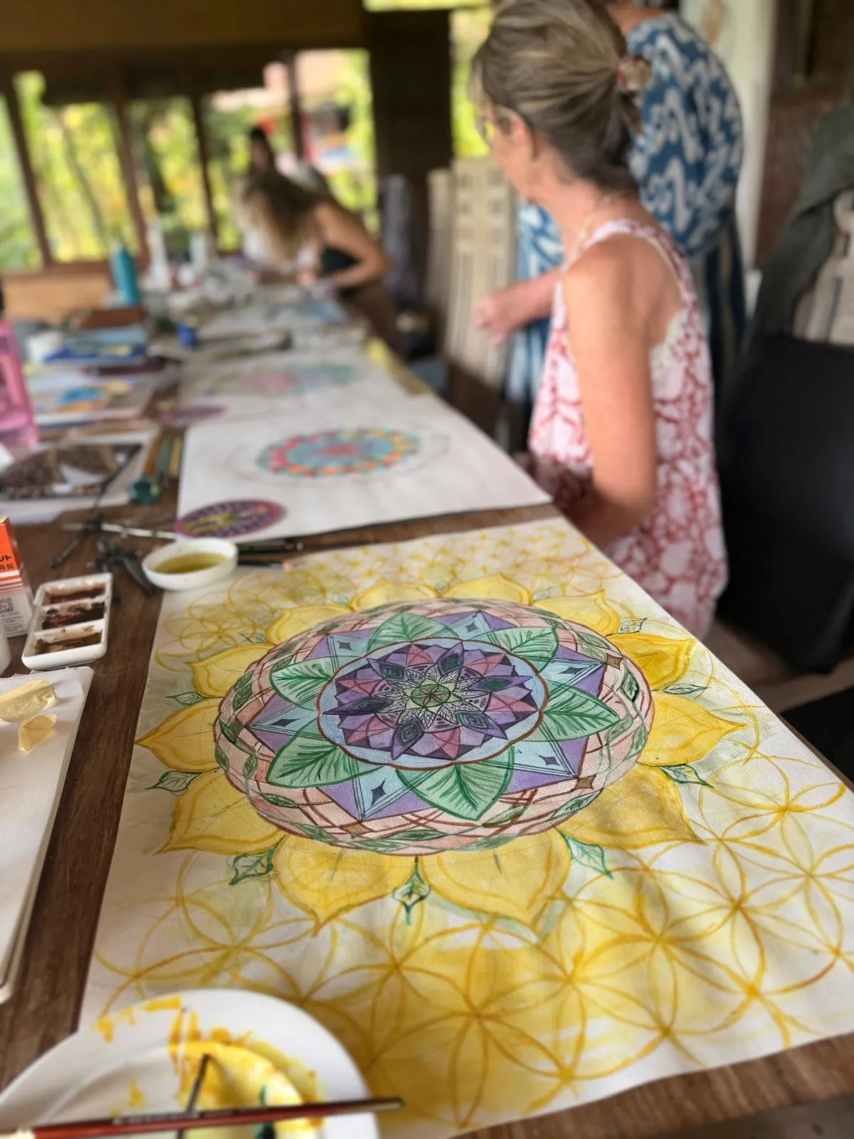 Watercolour mandalas laid out along a long wooden table