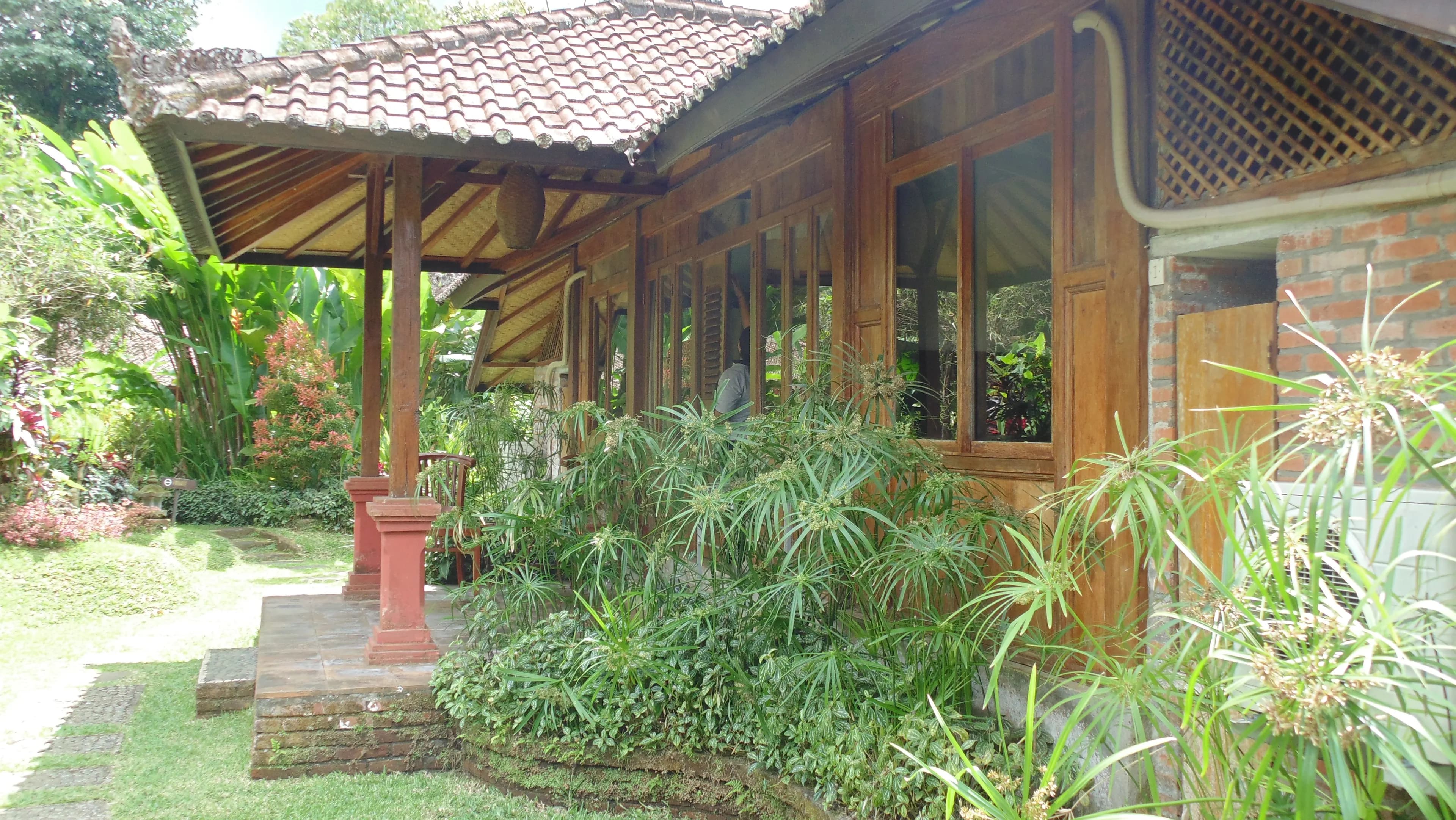Teak guest house with a clay-tiled roof and veranda among the gardens