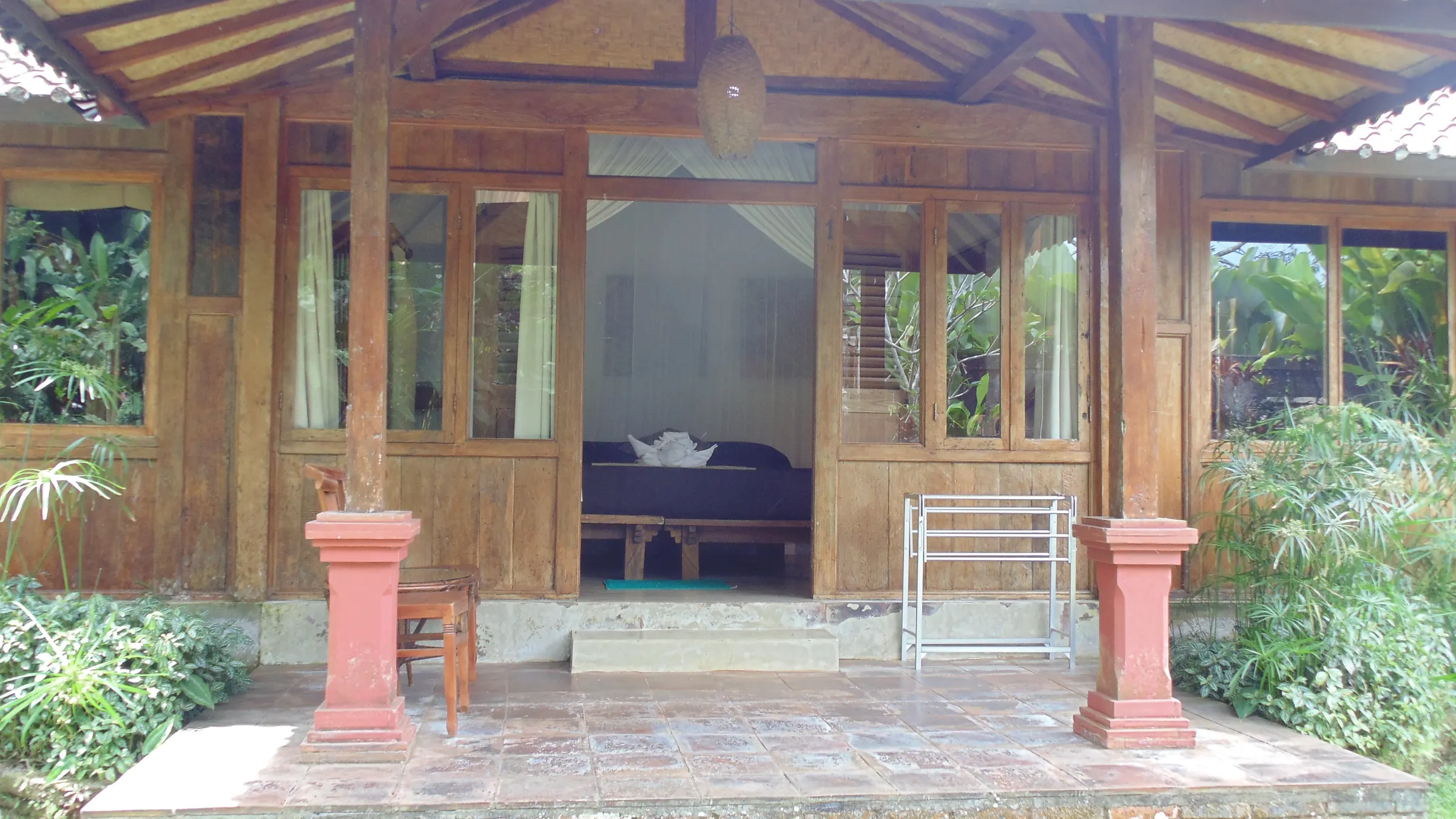 Teak veranda with double doors open onto a canopy bed