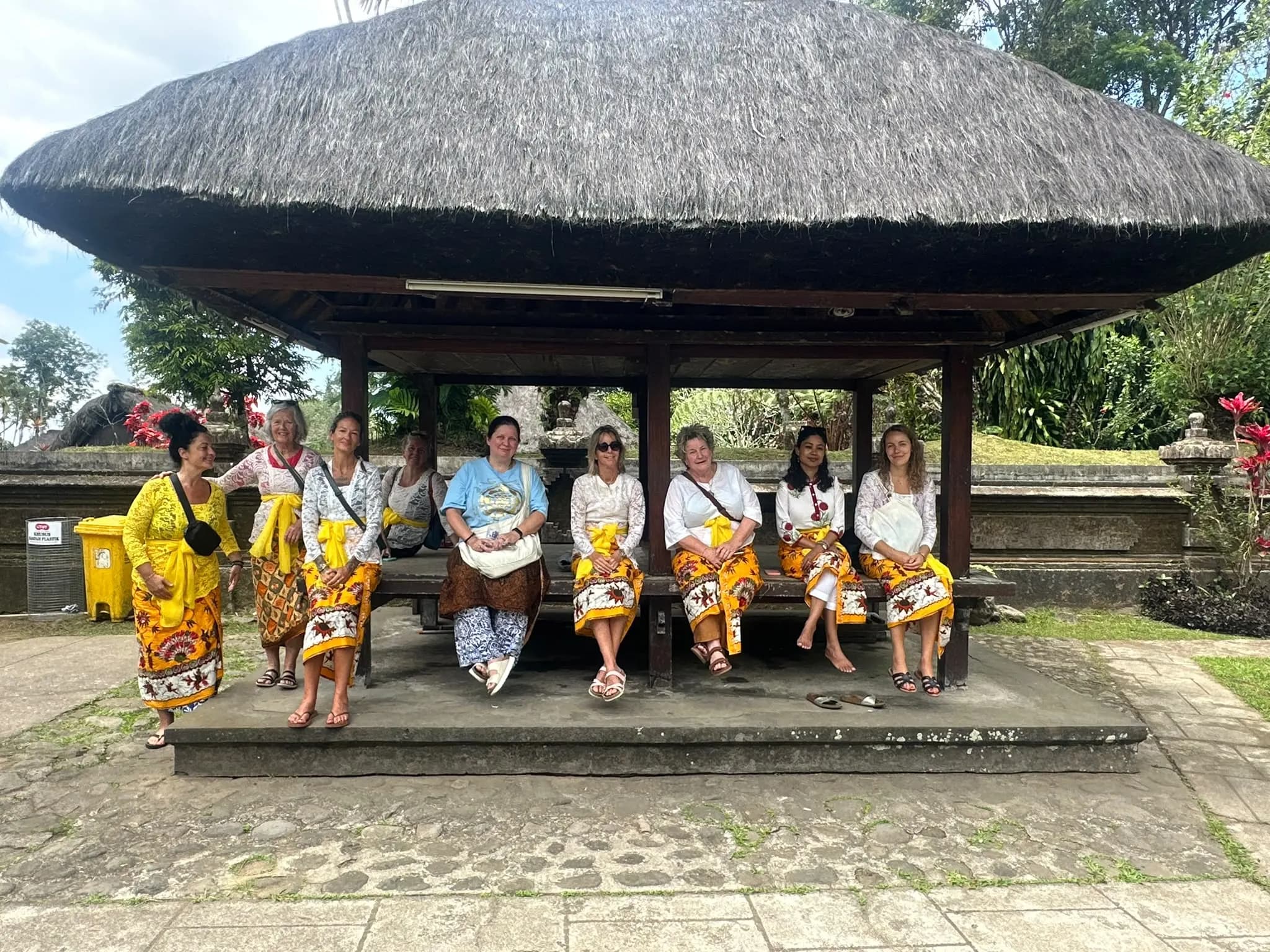 Guests in temple dress resting under a thatched temple bale
