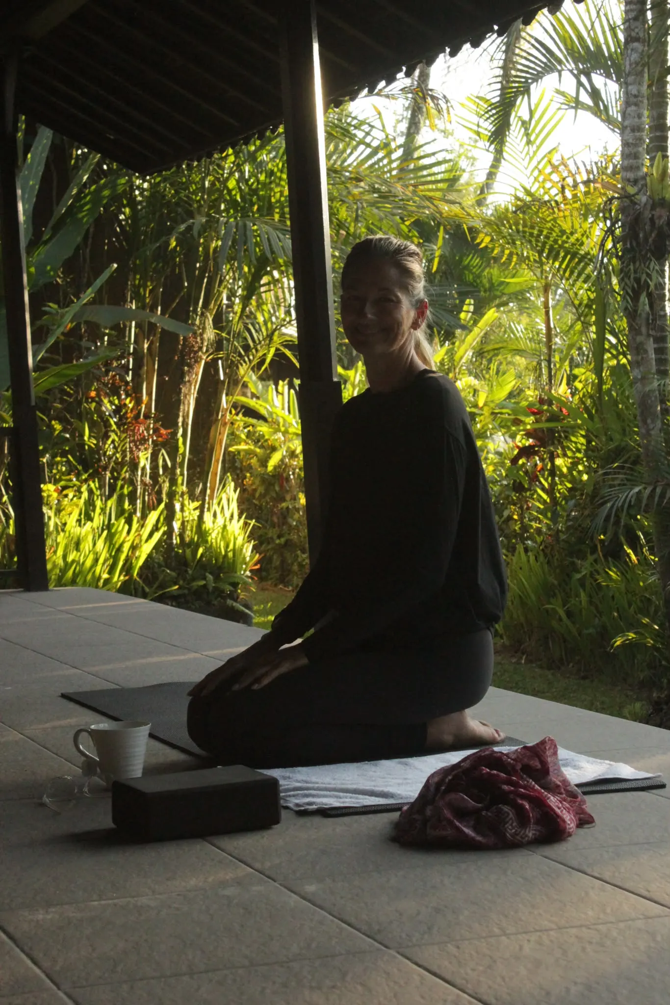 Yoga in the open pavilion, backlit by the sunlit tropical garden