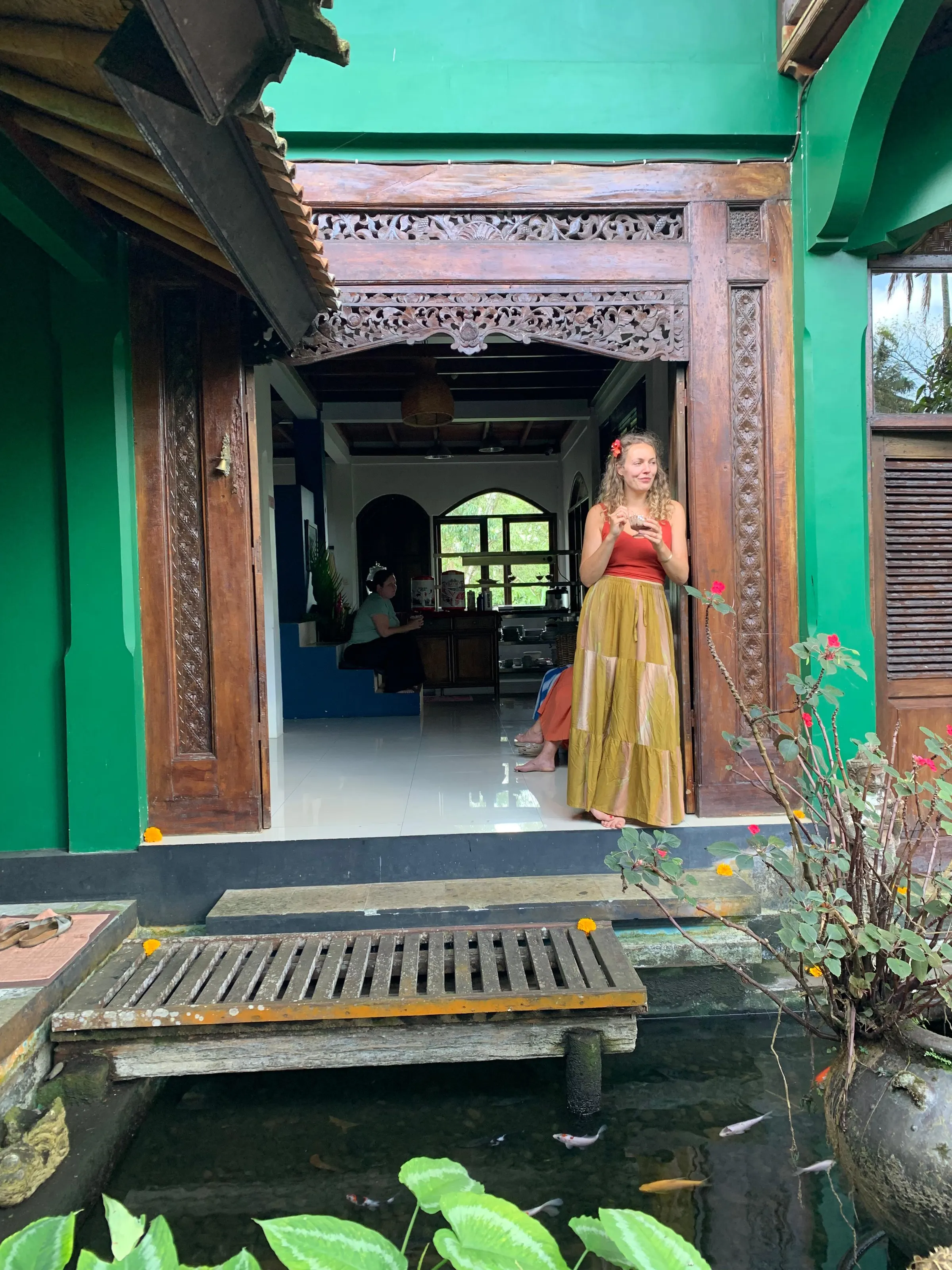 A carved Javanese teak doorway above a koi pond