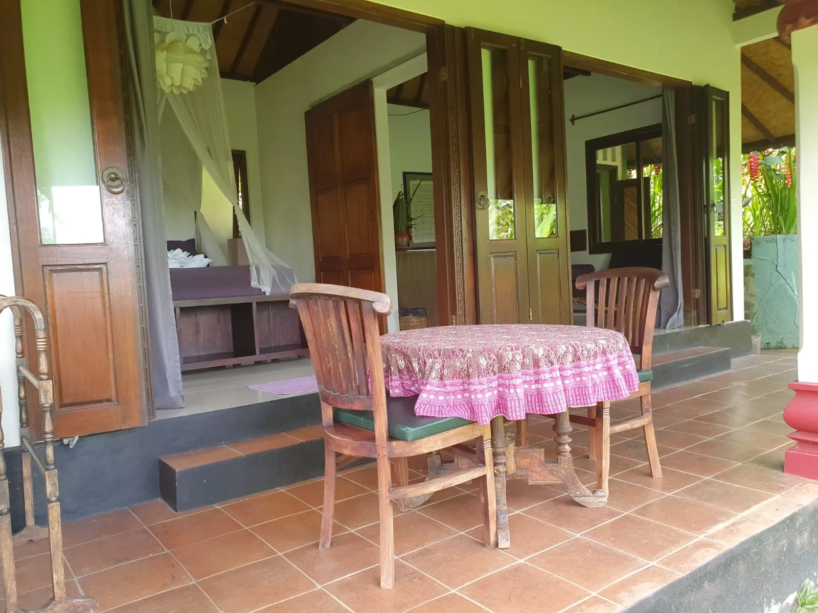 The Lotus House veranda with a batik-covered table and carved double doors