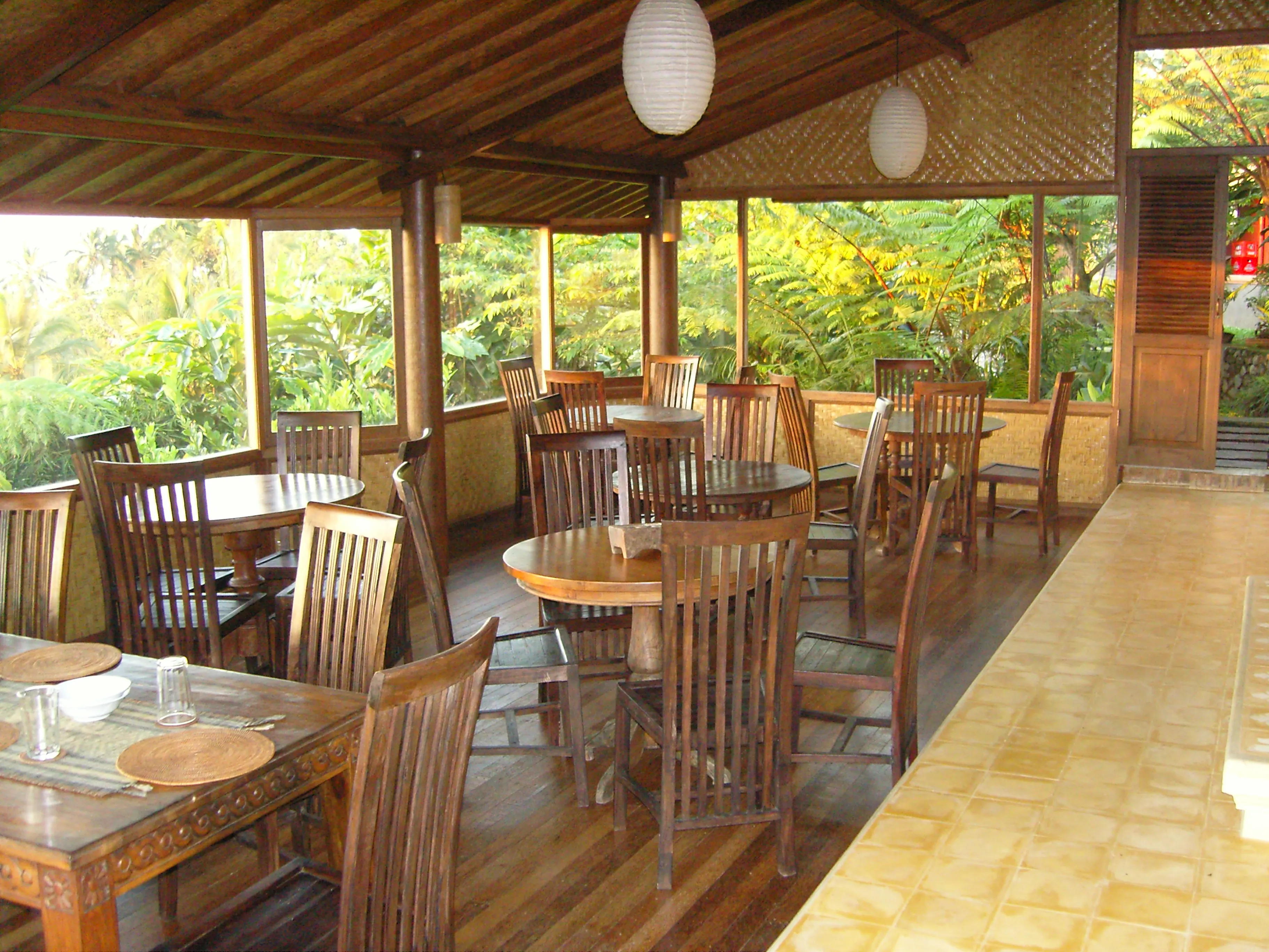 The open-sided timber restaurant with its round tables and a view into the jungle