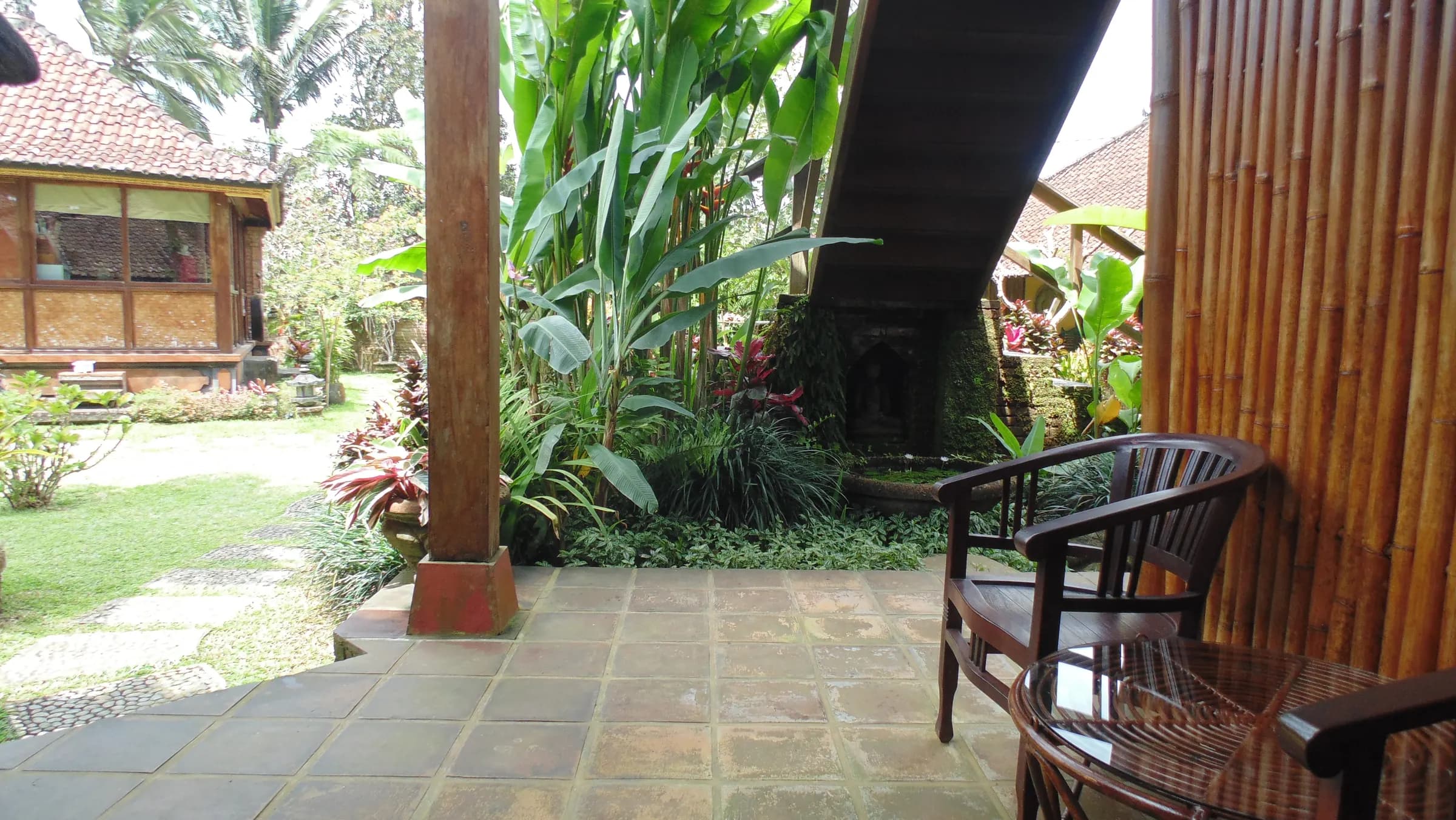 A bamboo-screened terrace looking over the garden to a stone shrine